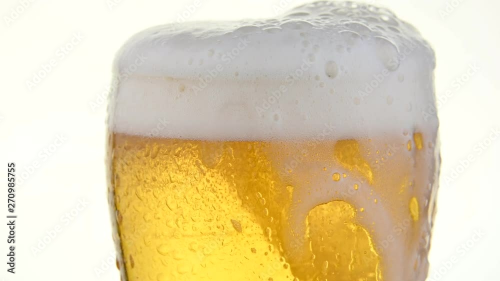 Close up pouring lager beer in glass over white Close up pouring lager beer in glass over white