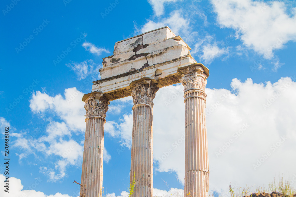 Obraz premium Ruins of Roman empire. Columns of temple of Castor and Pollux on Roman Forum (Forum Romanum), blue sky in background, Rome, Italy