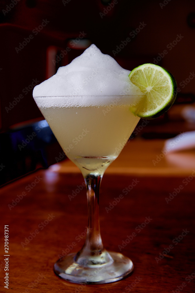 Summer fresh salt foam margarita with lime garnish on bar top in restaurant Summer fresh salt foam margarita with lime garnish on bar top in restaurant