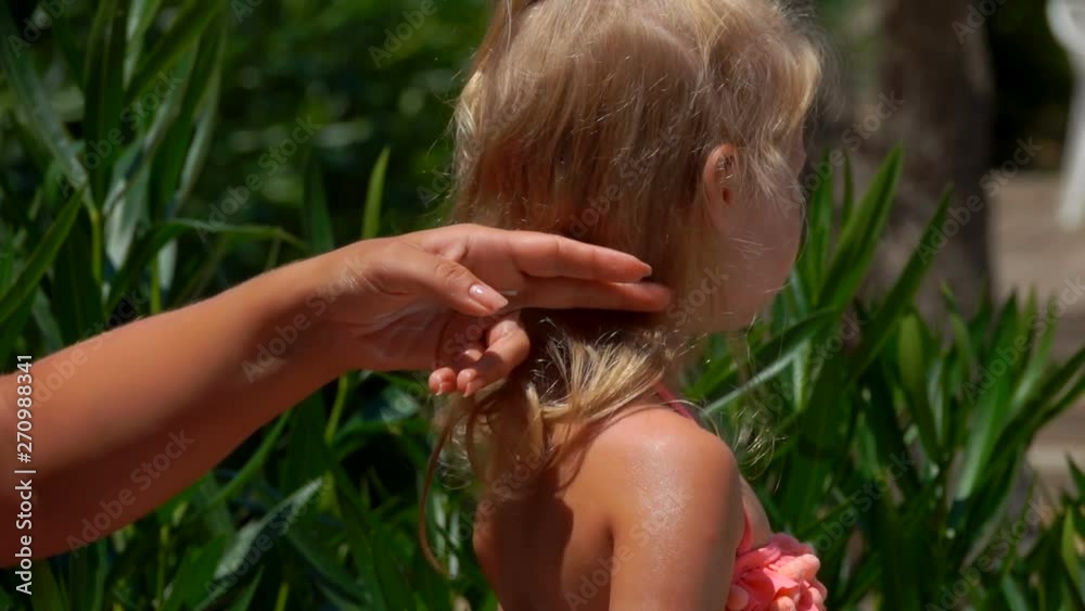 Female hand smears protective cream on the back of a little girl Female hand smears protective cream on the back of a little girl
