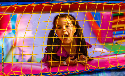 Slika na platnu Happy little girl having lots of fun on a jumping castle during sliding