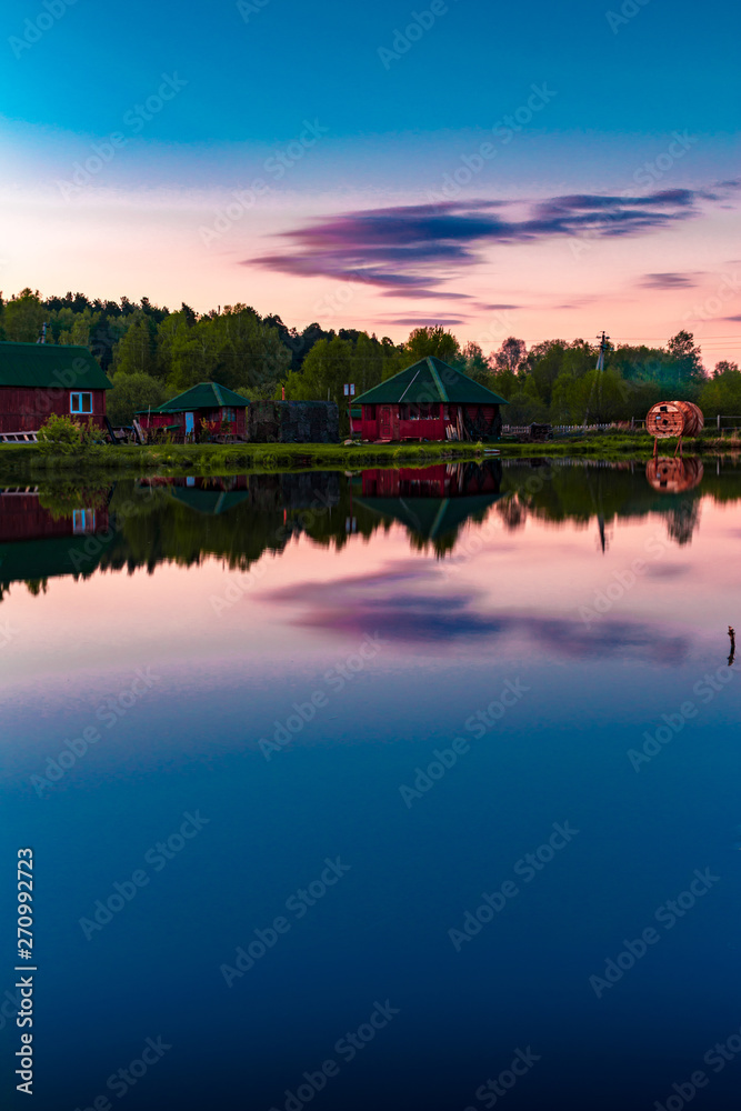 Small village red houses reflects in clearly still water at evening