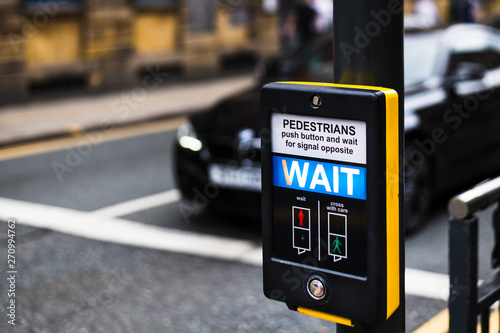 Fotografiet Pedestrian Crossing button in Leeds City Centre that says WAIT for people to cro