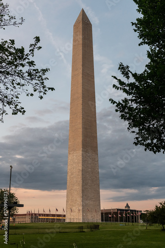 The Washington Monument at sunset, framed by trees and leaves