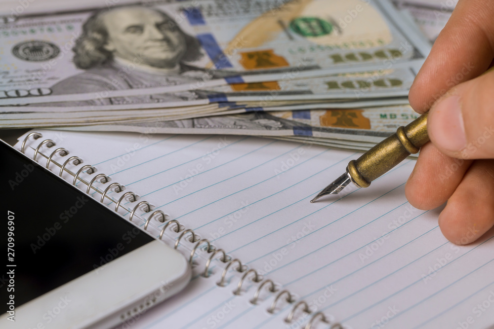 Empty notepad on man hand writes dollar banknotes with pen Empty notepad on man hand writes dollar banknotes with pen