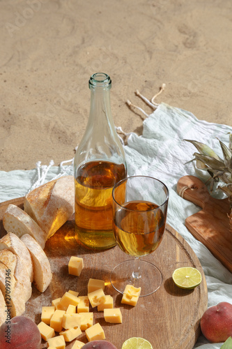 Picnic on a sandy beach with white wine, snacks and fruit on a blue plaid. photo