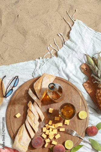 Picnic on a sandy beach with white wine, snacks and fruit on a blue plaid. photo