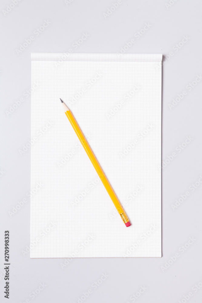 Grid note pad with pencil on gray background Grid note pad with pencil on gray background