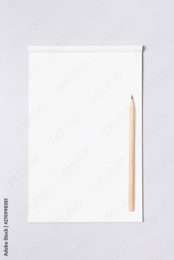 Grid note pad with pencil on gray background Grid note pad with pencil on gray background