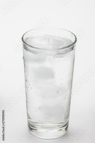 Glass of ice water with green leaf for fresh on white 