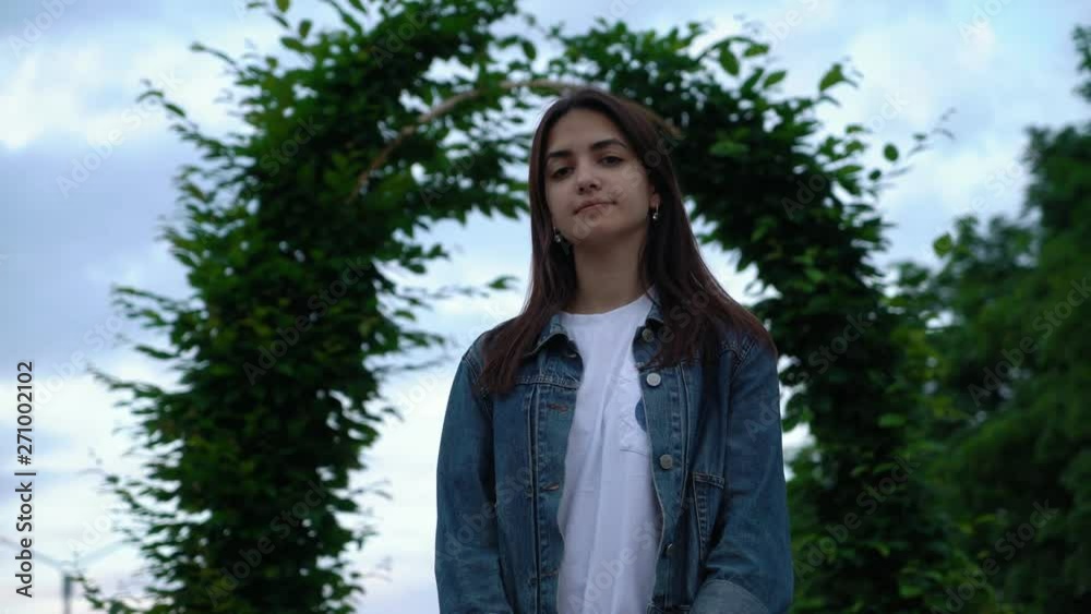 cute brunette young girl in jeans jacket smiling on the street in the park in the evening cute brunette young girl in jeans jacket smiling on the street in the park in the evening