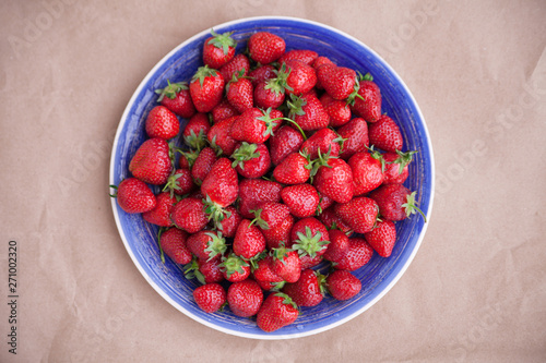 A large bright blue dish with ripe strawberries. View from above. Concept of summer mood and healthy eating.