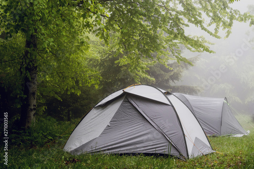 Camping in the nature, tents in the mountain range in a misty fog rainy day