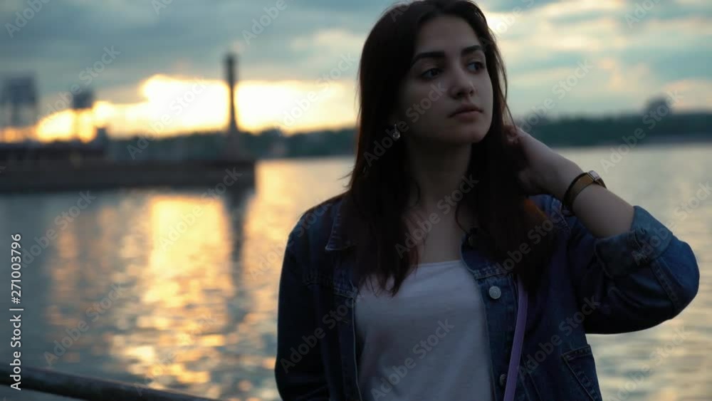 silhouette of cute smiling young girl near the water on the quay at sunset silhouette of cute smiling young girl near the water on the quay at sunset