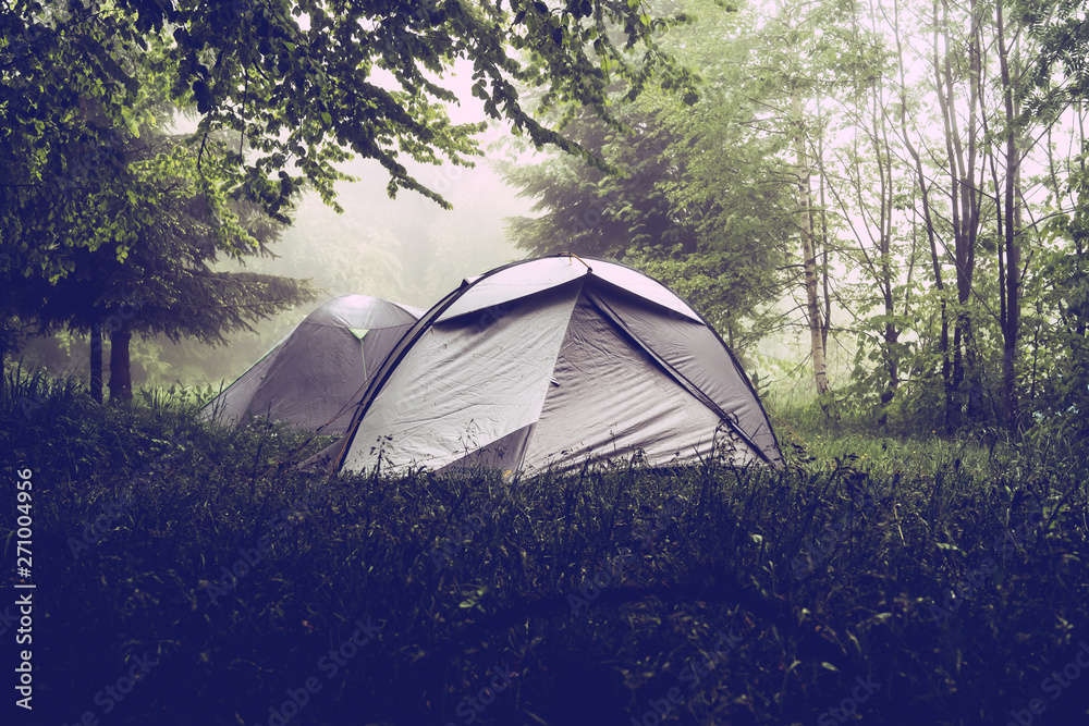 Camping in the nature, tents in the mountain range in a misty fog rainy day