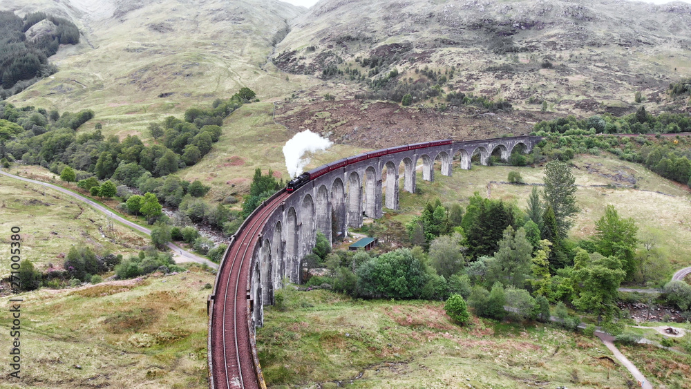 Steam Train crossing the Glenfinnan Viaduct, aerial view by drone - Scotland, UK