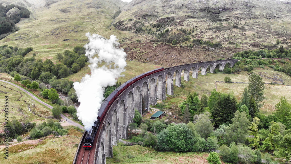 Steam Train crossing the Glenfinnan Viaduct, aerial view by drone - Scotland, UK