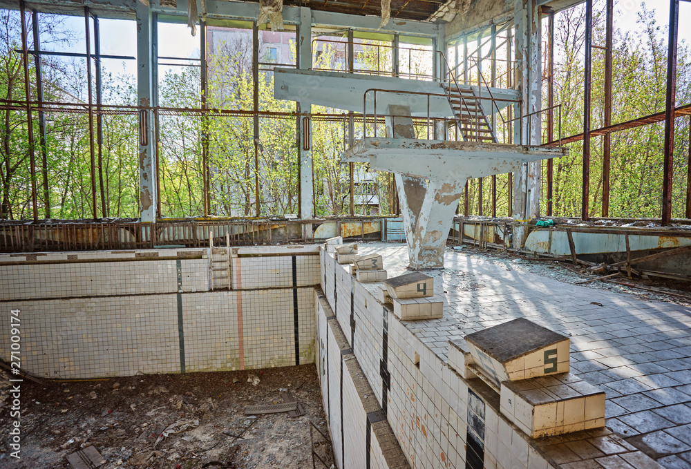 Abandoned swimming pool in Pripyat. Destroyed gym in a radioactive city. The street is overgrown with trees and bushes.