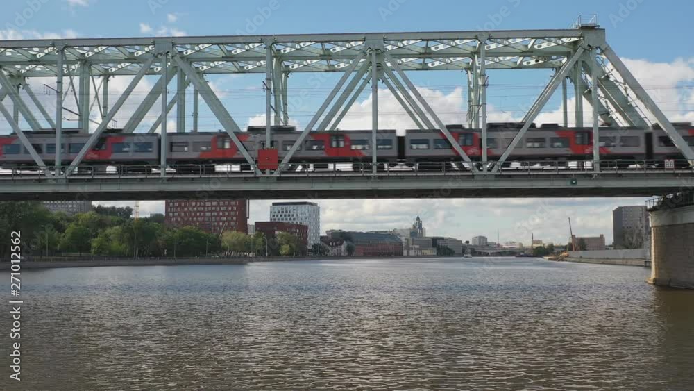 Aerial view of the railway bridge, with a moving train on it, across the river flowing through a major city Aerial view of the railway bridge, with a moving train on it, across the river flowing through a major city