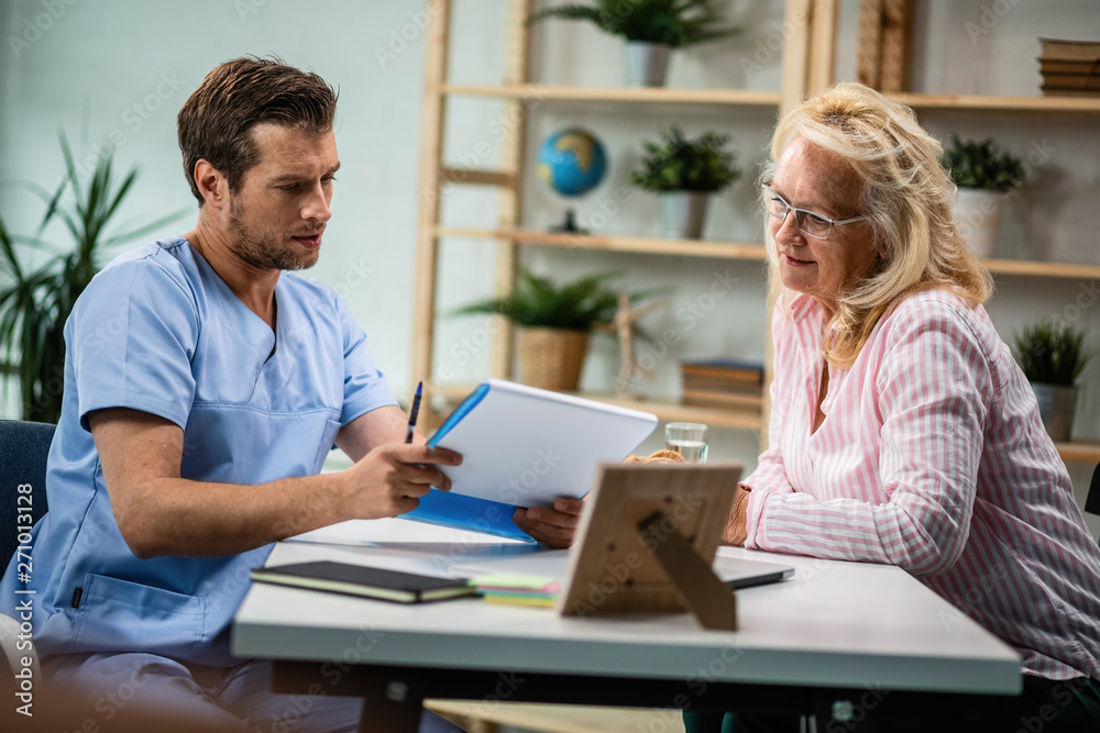 General practitioner and mature woman going through medical documents together. General practitioner and mature woman going through medical documents together.