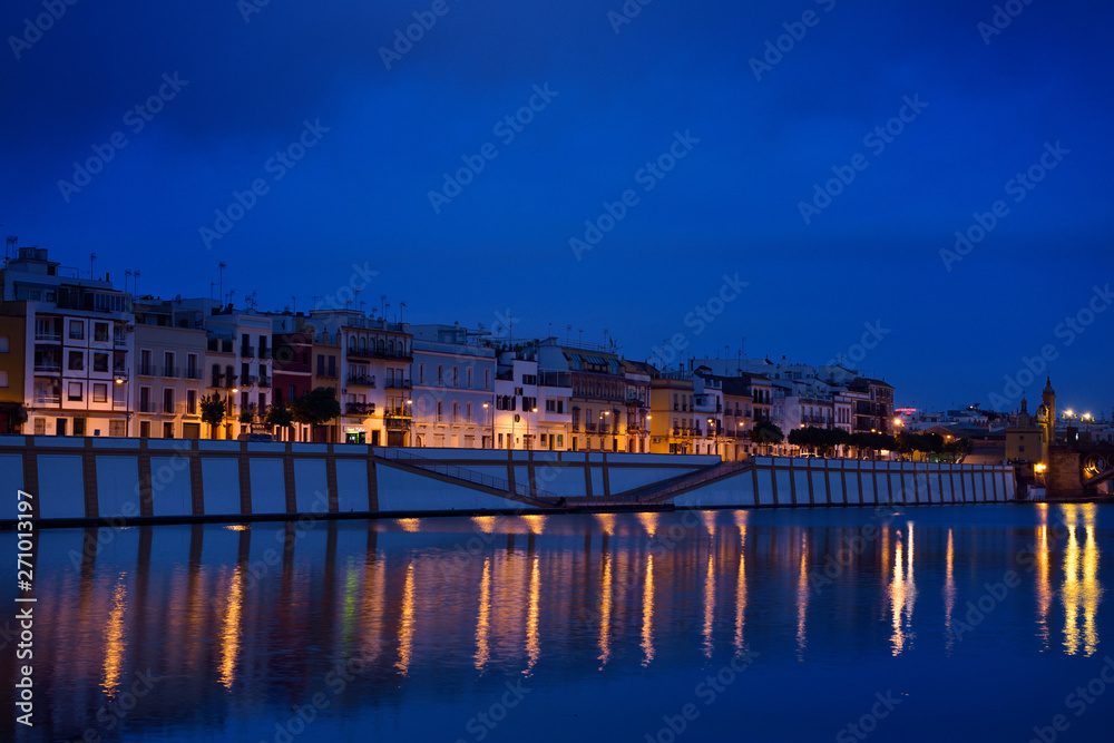 Houses on Betis street to Isabel bridge Seville with Chapel of the Virgin of Carmen at dawn at Alfonso XIII Canal