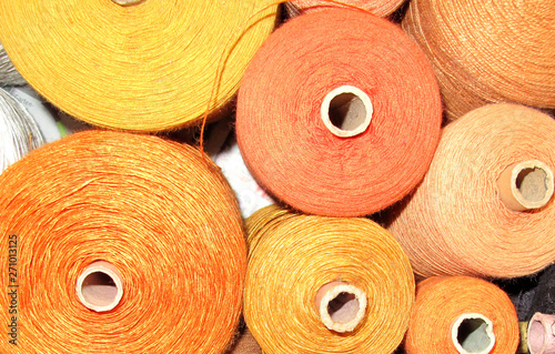 Weaving yarn in yellow tones on spools