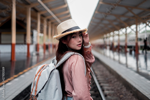 Smiling woman traveler looking camera with backpack on holiday relaxation at the train station,relaxation concept, travel concept