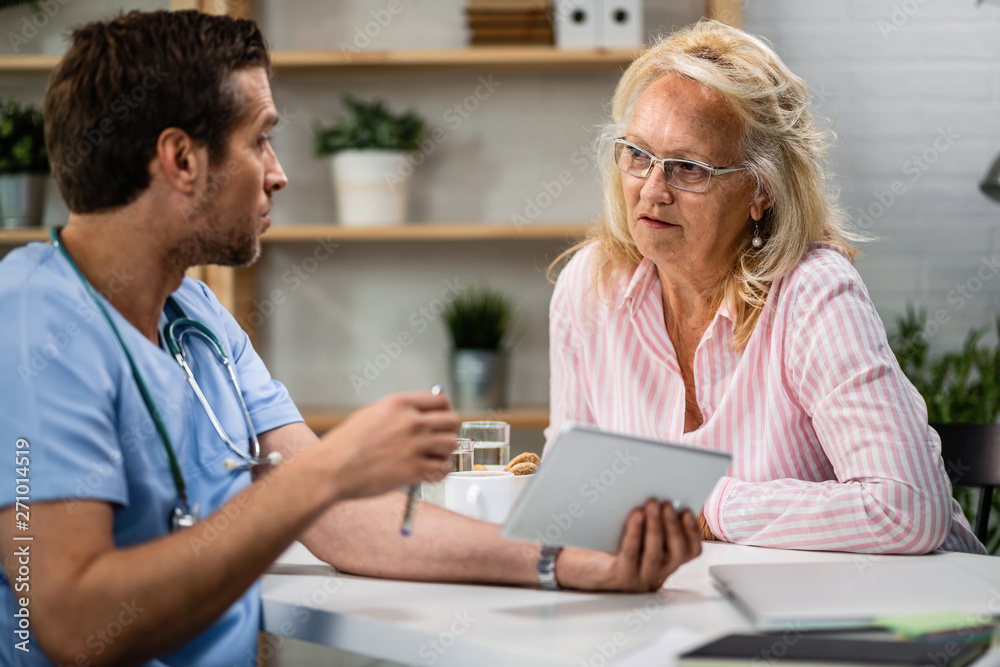 Mature woman talking to a doctor who is sing touchpad during the consultations. Mature woman talking to a doctor who is sing touchpad during the consultations.