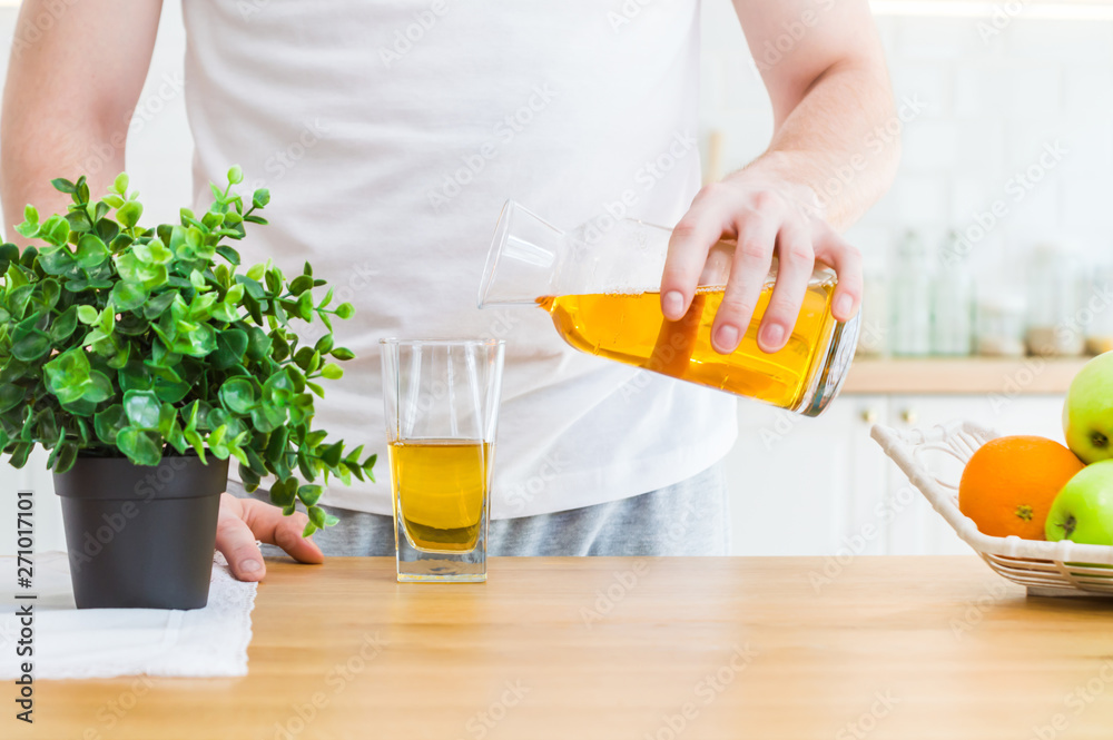 Man pouring apple juice from jug into glass in the kitchen. Man pouring apple juice from jug into glass in the kitchen.