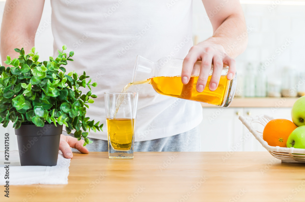 Man pouring apple juice from jug into glass in the kitchen. Man pouring apple juice from jug into glass in the kitchen.