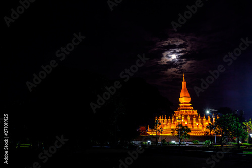 Golden Pagoda, the architecture of Laos, Phra That Luang at night  bright illuminated large moon.with Lens flare ligh .on black background .Vientiane, Laos