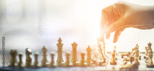 The businessman's hand is picking up chess. Who is the commander To play successfully in the competition for victory, concept, strategy, management or leadership