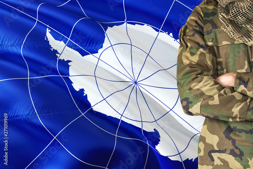 Crossed arms soldier with national waving flag on background - Antarctica Military theme.
