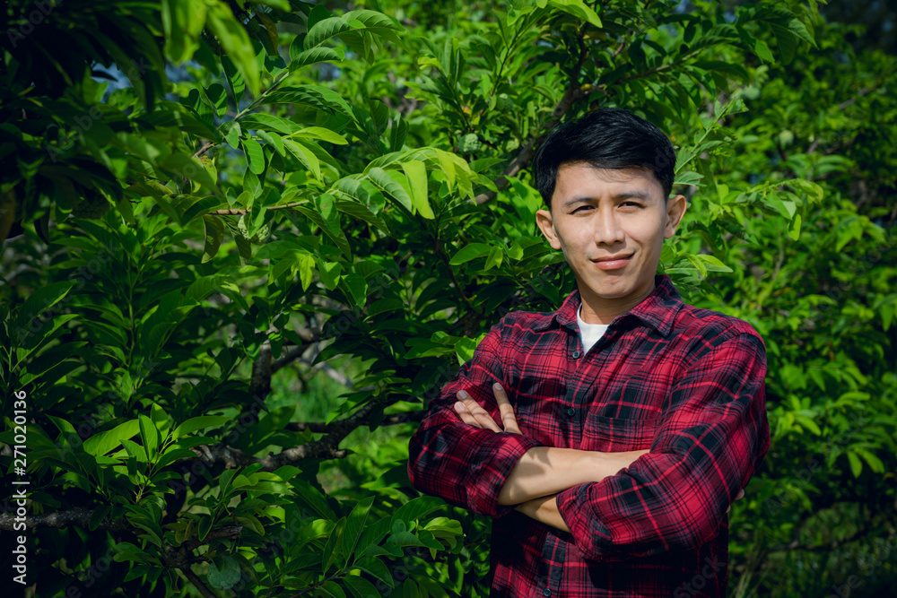 Young man farmer smiling and standing in custard apple trees orchard background. Young man farmer smiling and standing in custard apple trees orchard background.