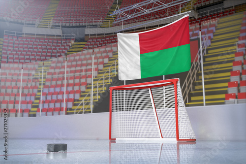 Flag of Madagascar in hockey arena with puck and net