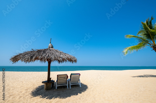 Beach chairs  umbrella and palms on sandy beach near sea. island in Phuket  Thailand. Travel inspirational  Summer holiday and vacation concept for tourism relaxing.