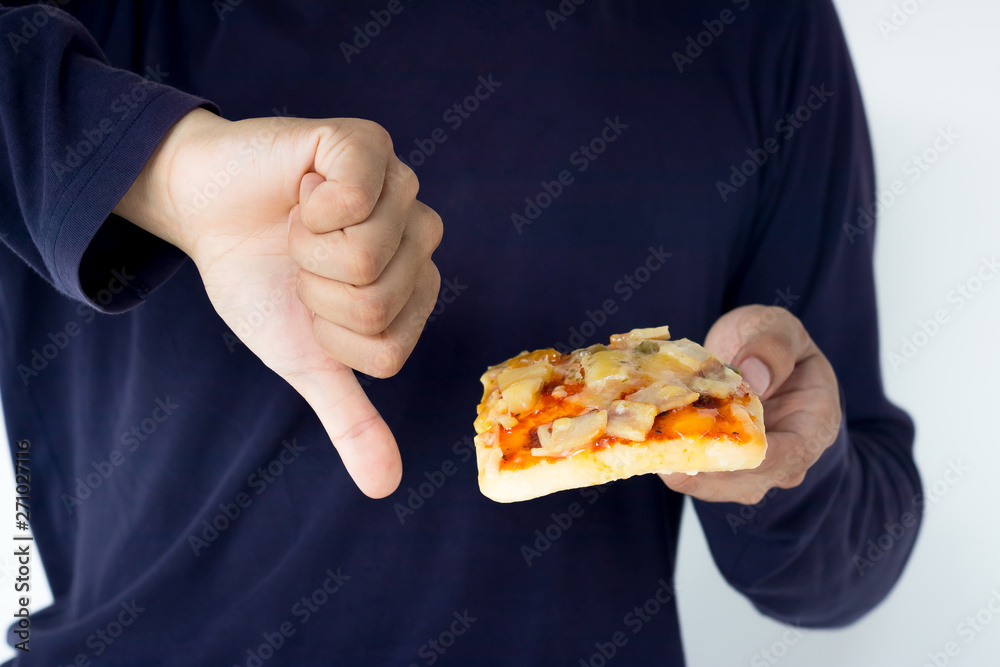 Young man rejecting pizza or unhealthy food showing thumbs Down. Dieting or good health concept. Unhealthy Eating Concept.