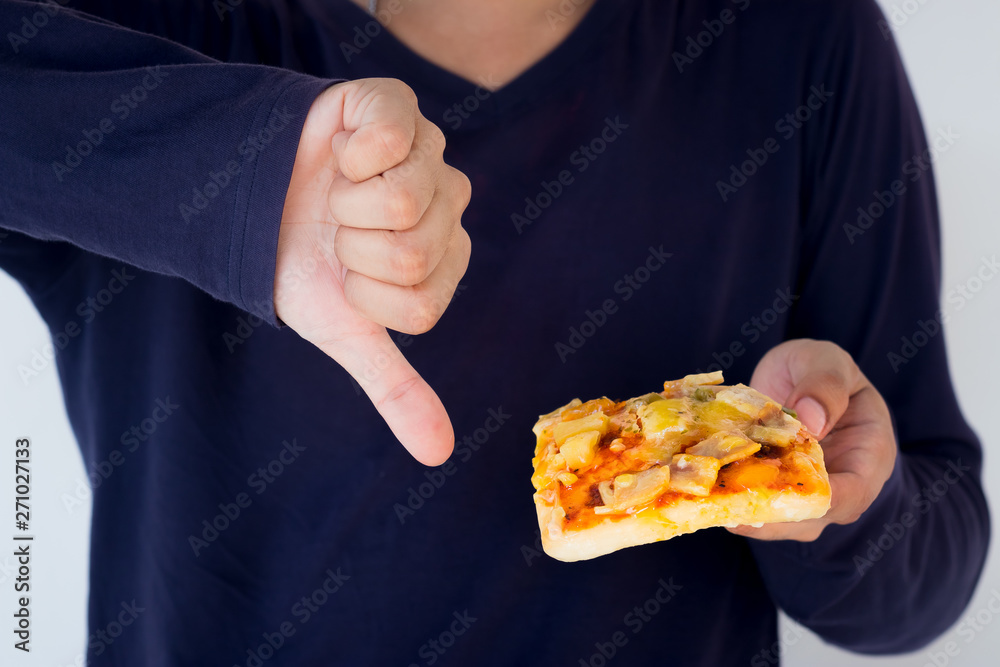 Young man rejecting pizza or unhealthy food showing thumbs Down. Dieting or good health concept. Unhealthy Eating Concept.