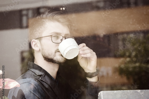handsome man drinking coffee. Photo behind glass