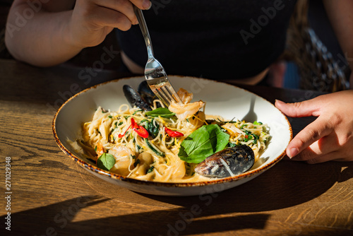 woman eating seafood pasta in the cafe