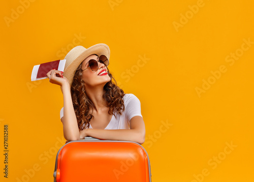 concept of travel. happy woman girl with suitcase and passport on yellow background