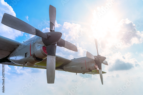 Schilderij op canvas Two Engine Aircraft Propeller of Turboprop Airplane Flying High in Cloudy Sky with Sun Shine Brightly