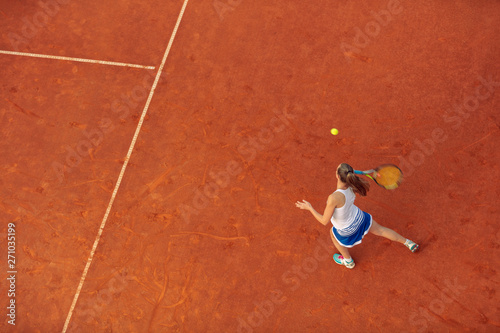 Aerial shot of a female tennis player on a court during match. Young woman playing tennis.High angle view. © FS-Stock
