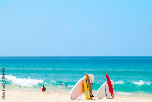 Fototapeta Naklejka Na Ścianę i Meble -  Surfboard on sand tropical beach with sea wave and blue sky background. Summer vacation background concept. - Image