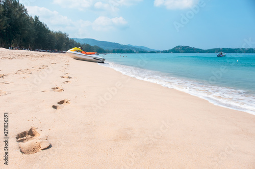 Footprints and sea wave on sandy beach with blue sky. Landscape of tropical beach in summer. Holiday background concept - Image
