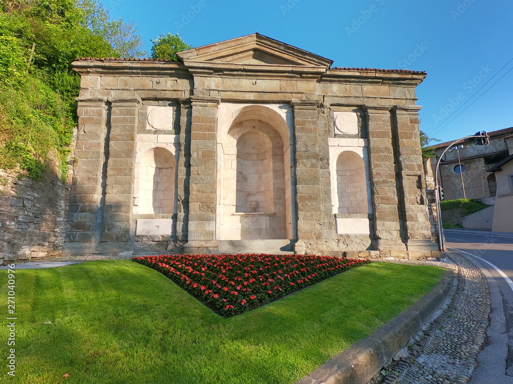 Obraz premium Bergamo, Italy. The old town. Landscape at the old fountain Saint Agostino in summer with flowers