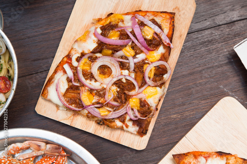 Hot pizza slice with melted mozzarella cheese and tomato on wood board photo