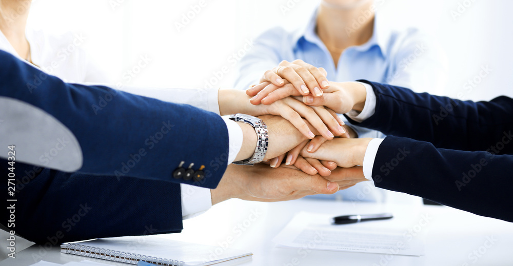 Business team showing unity with their hands together. Group of people joining hands and representing concept of friendship, teamwork and partnership