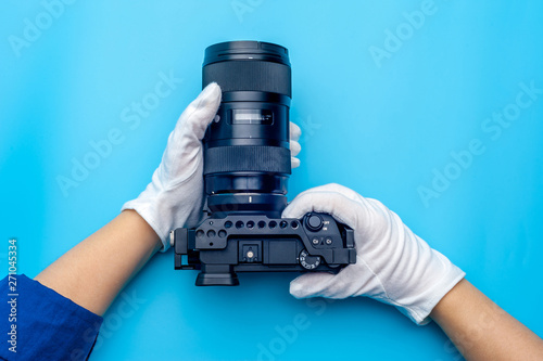 Top view female hand wearing white gloves holding professional camera photo