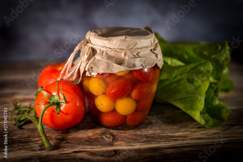 Homemade canned cherry tomatoes on rustic background